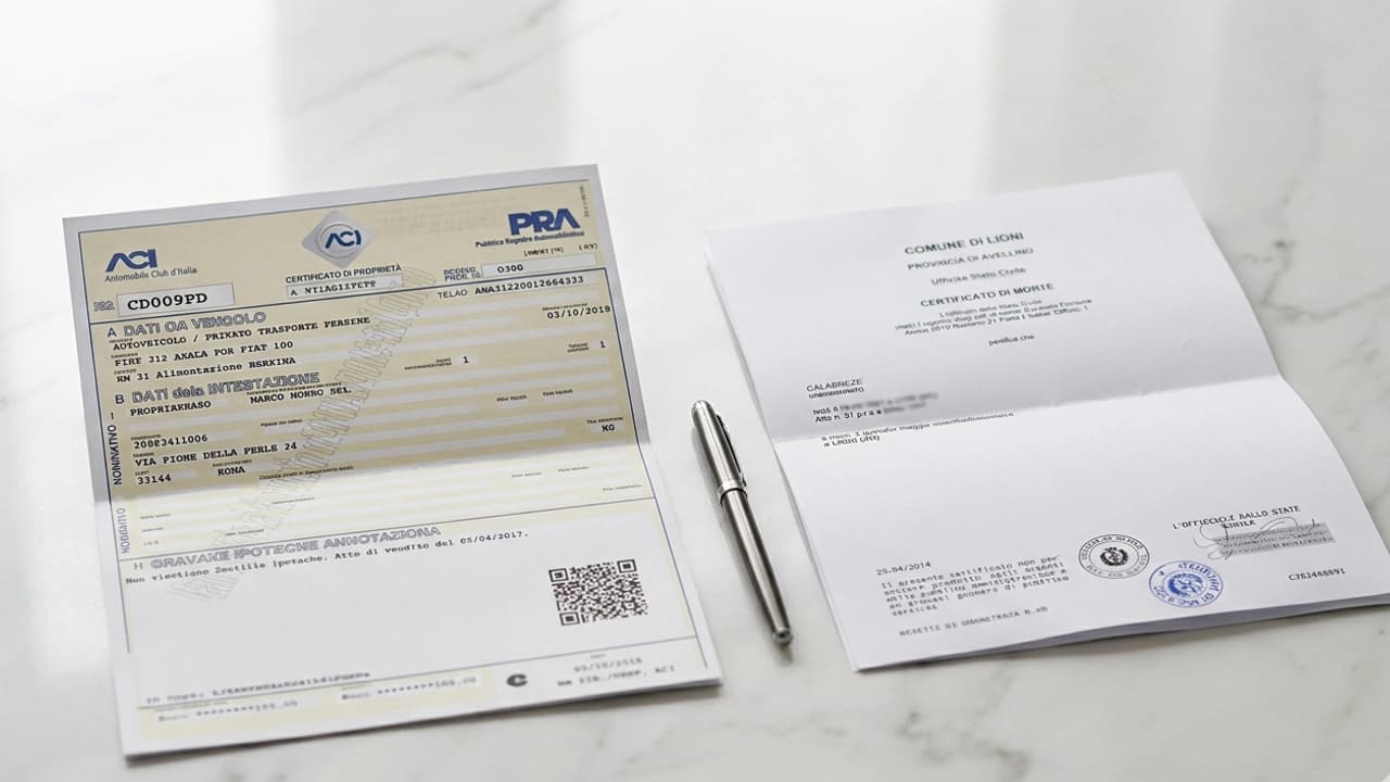 Certificato di proprietà e certificato di morte su superficie in marmo — procedura successione auto PRA 2026