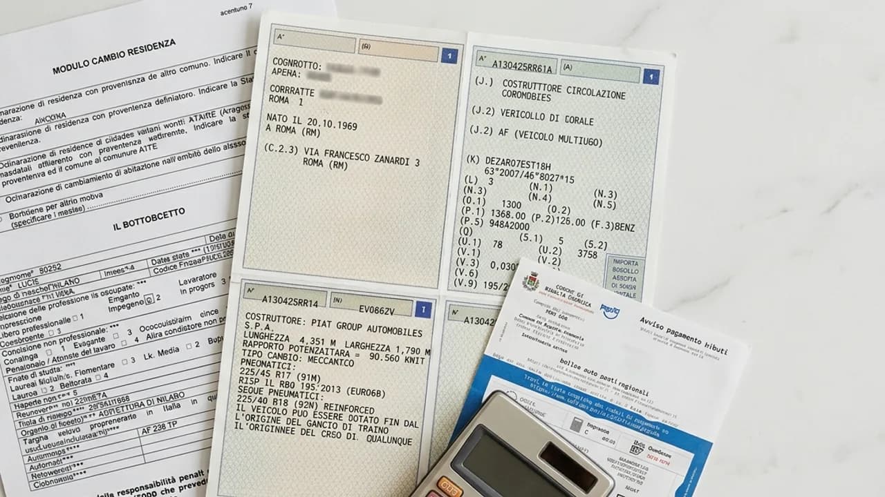 Modulo di cambio residenza, carta di circolazione e ricevuta bollo auto su scrivania, con calcolatrice per la nuova tariffa regionale 2026