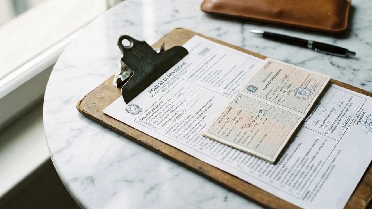 Revisione auto 2026: checklist tecnica e carta di circolazione italiana su piano bianco, luce naturale